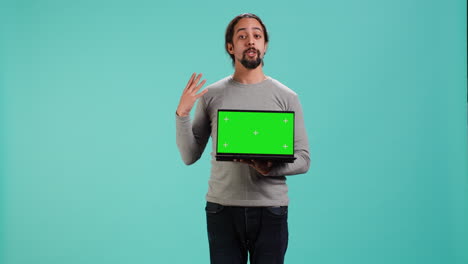 hombre presentando una pantalla verde portátil, aislado sobre el fondo del estudio