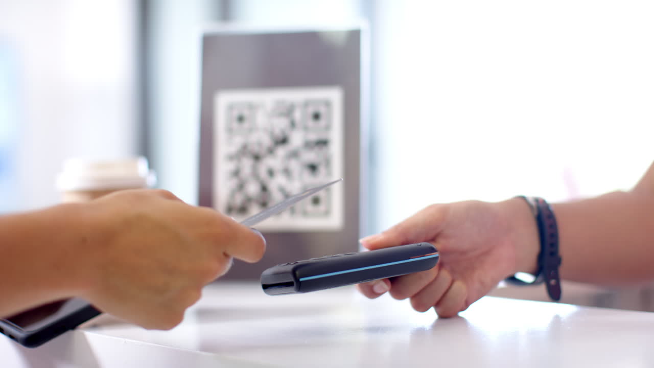 A person is handing over credit card to another, with a QR code in background