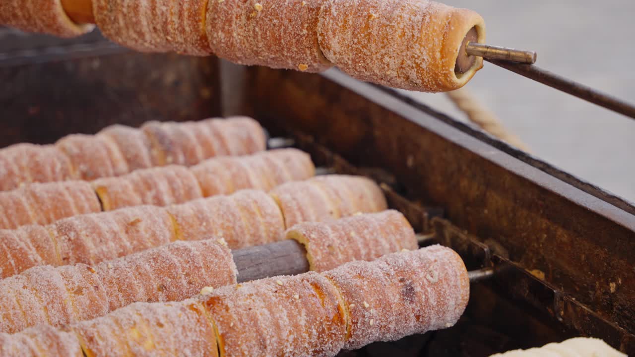 Fresh dough wrapped on rollers beginning to brown with soft pale crust forming at the edges
