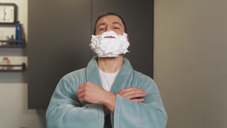 a happy man with foam on his beard admires himself in front of the mirror