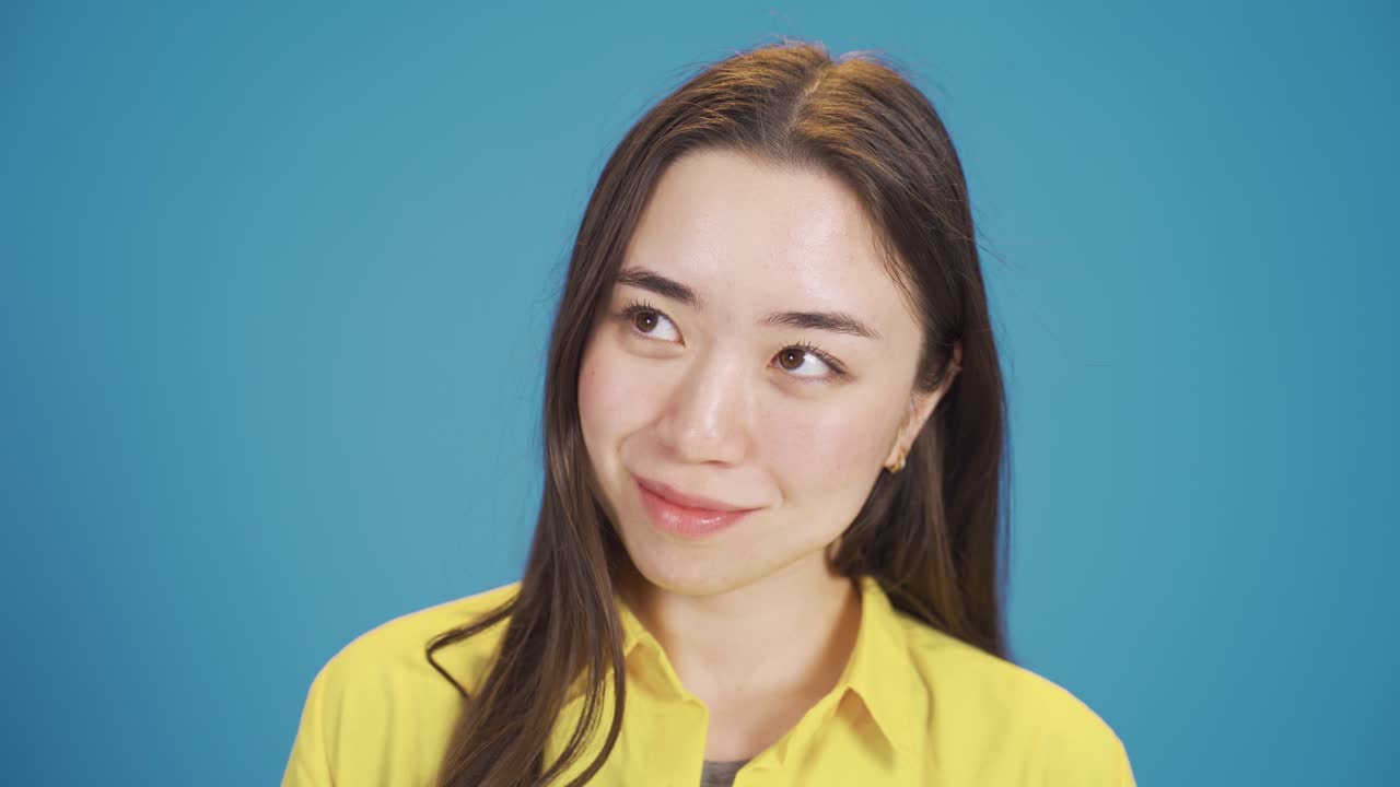 긍정적인 행복한 젊은 아시아 여성이 생각하고, 꿈을 꾸고, 웃고 있습니다.