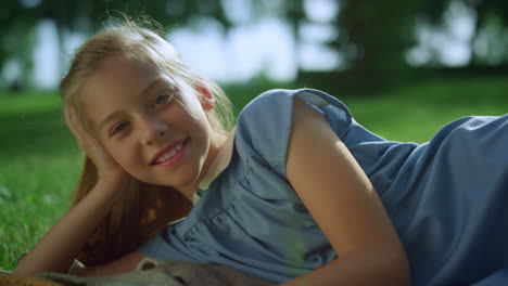 smiling girl lying blanket in warm sunlight looking in camera close up.