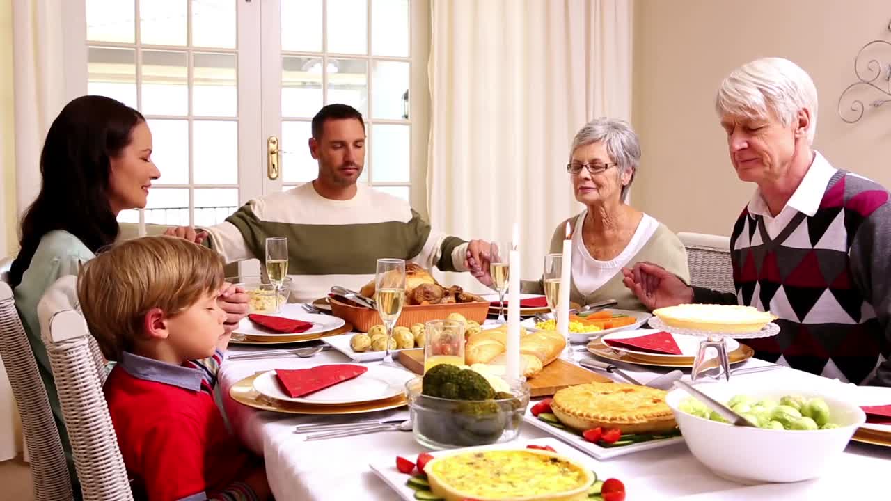 Three generation family saying grace before christmas dinner together
