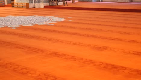 interior of a mosque with red prayer rug and blue and white tile design