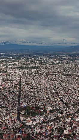 mexico city skyline and volcanoes on a cloudy day, seen from above