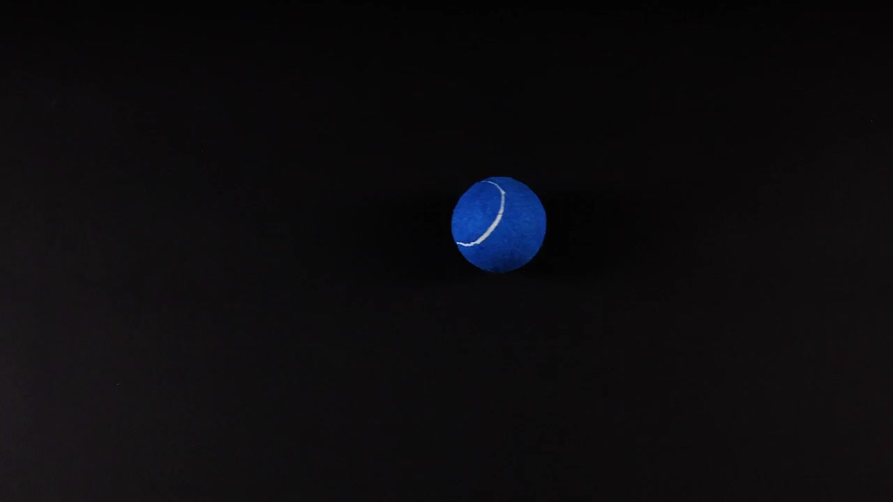 Blue tennis balls moving against black background