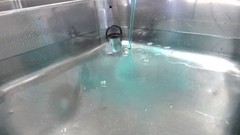 se vierte un limpiador químico azul en lavabos llenos de agua