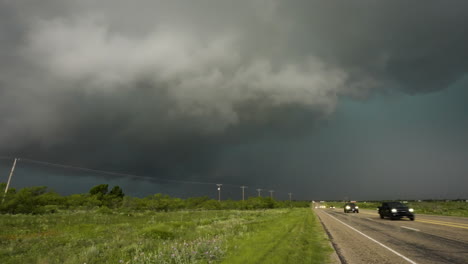 huge storm looming over busy road with cars driving away