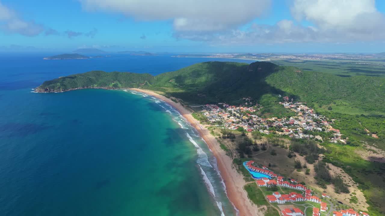 Splendide riprese aeree con drone di Praia de Tucuns a Buzios, Brasile. Una bellissima spiaggia sabbiosa incontra l'oceano blu intenso, incorniciata da lussureggianti colline verdi.