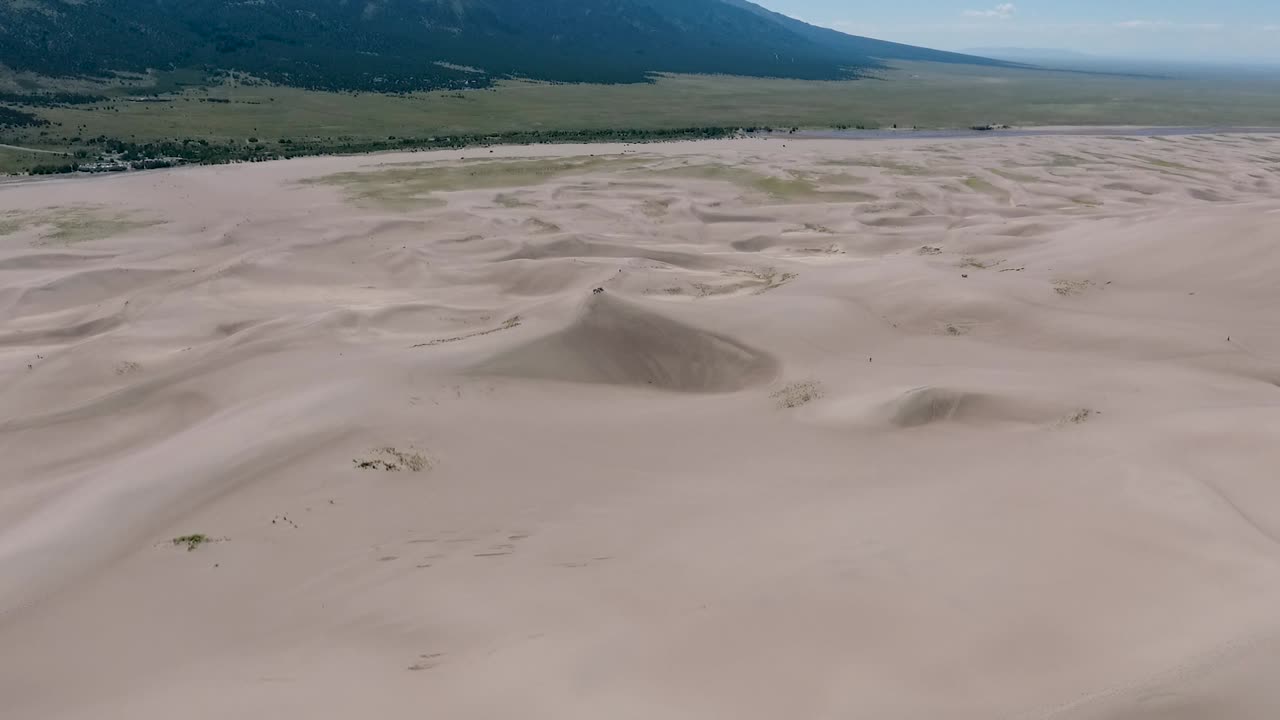 un espectacular avión no tripulado de alto vuelo, un paisaje filmado sobre las grandes dunas de arena de colorado, hogar de las dunas más altas de toda américa del norte, con las montañas de sangre de cristo en el fondo.