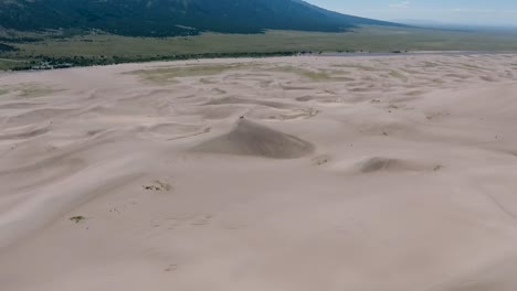 A-spectacular-high-flying,-landscape-drone-shot-over-the-Great-Sand-Dunes-of-Colorado,-home-to-the-tallest-sand-dunes-in-all-of-North-America,-with-the-Sangre-de-Cristo-Mountains-in-the-background