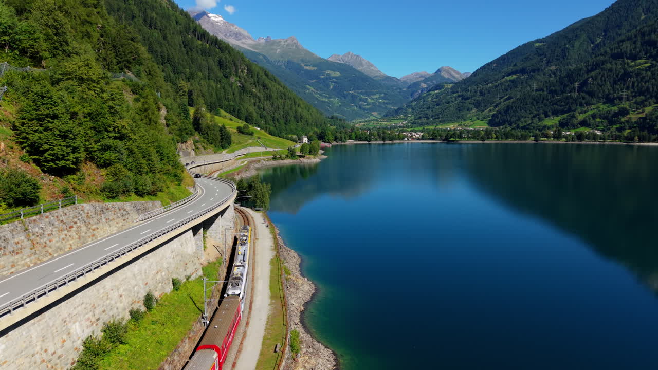 Scenic Swiss train by a lake and mountains on a sunny day
