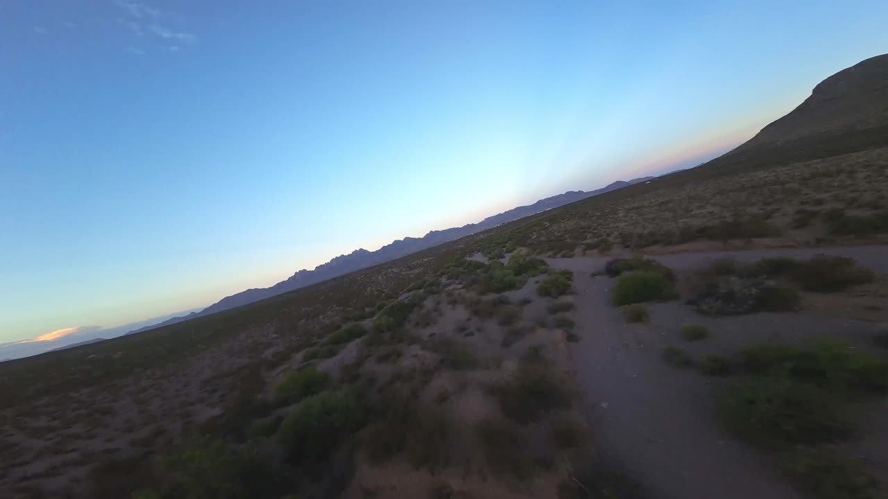 drone fpv volando sobre el desierto y las montañas en el paso, tx durante la puesta del sol