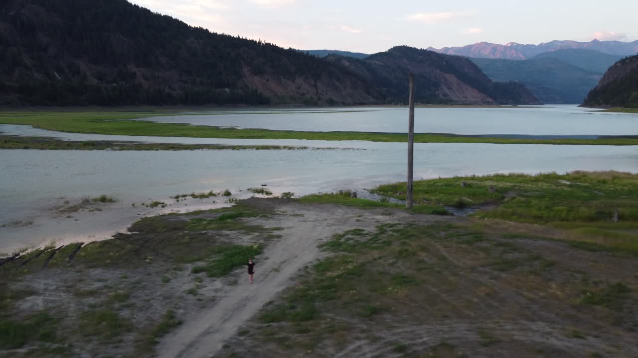 dama aérea drone caminando en la luz del atardecer a lo largo del río soo con fondo de montaña columbia británica canadá 4k