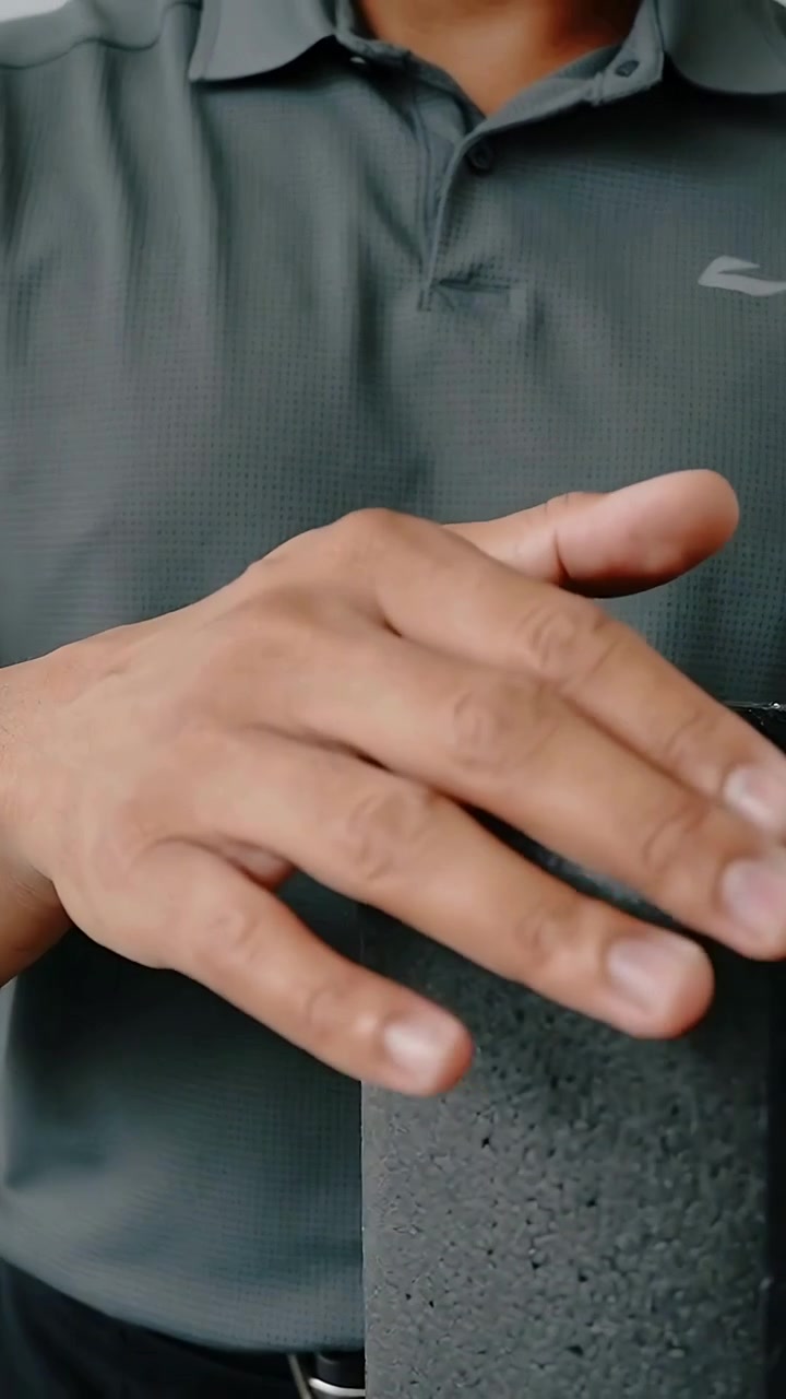 Vertical video: Camera pulling back male hands in polo using foam roller in studio, inspecting seam