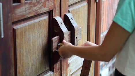 persona que desbloquea y abre una puerta tradicional