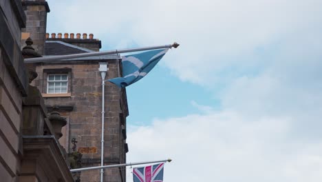 scottish flag on flagpole blown by wind on royal mile house, edinburgh