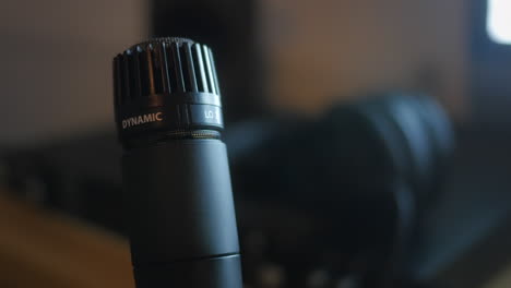A STATIC CLOSE UP SHOT of a classic dynamic microphone, rotating slowly in a home recording studio.