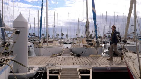 slow motion forward dolly shot of a young captain heading to his yacht in a marina