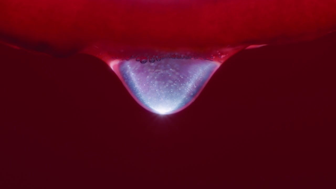 Scatto macro di una goccia d'acqua che cade da una fetta di frutto del drago
