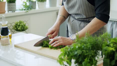 woman cutting parsley on wooden board