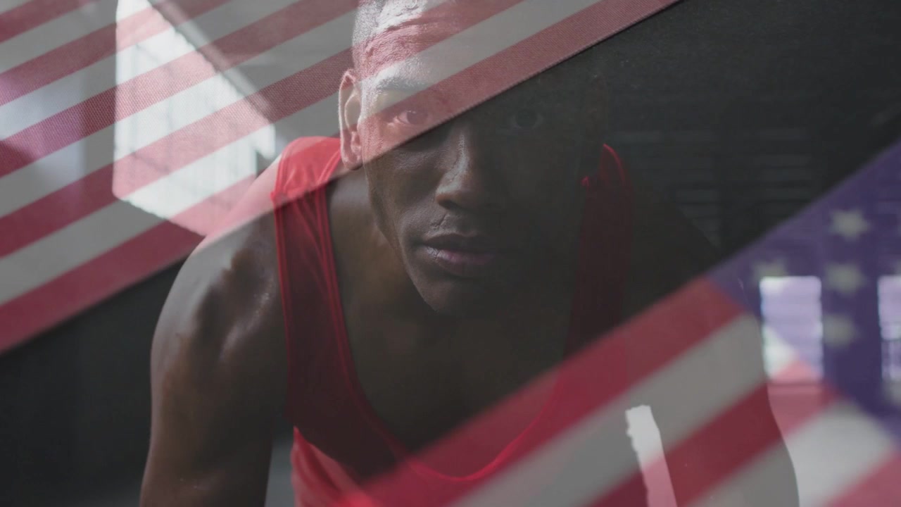 Male athlete starting rep, pushing up toward lens in gym, flag overlay moving over him, training