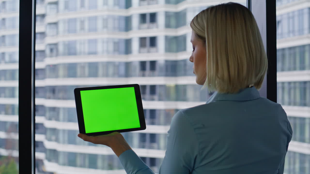Woman holding tablet with green screen in office