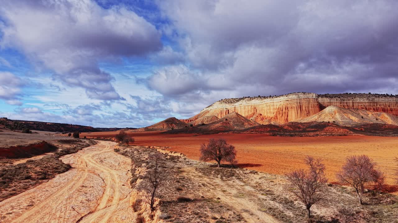 Vista di una strada sterrata che conduce a colline rocciose rosse in Spagna durante il giorno