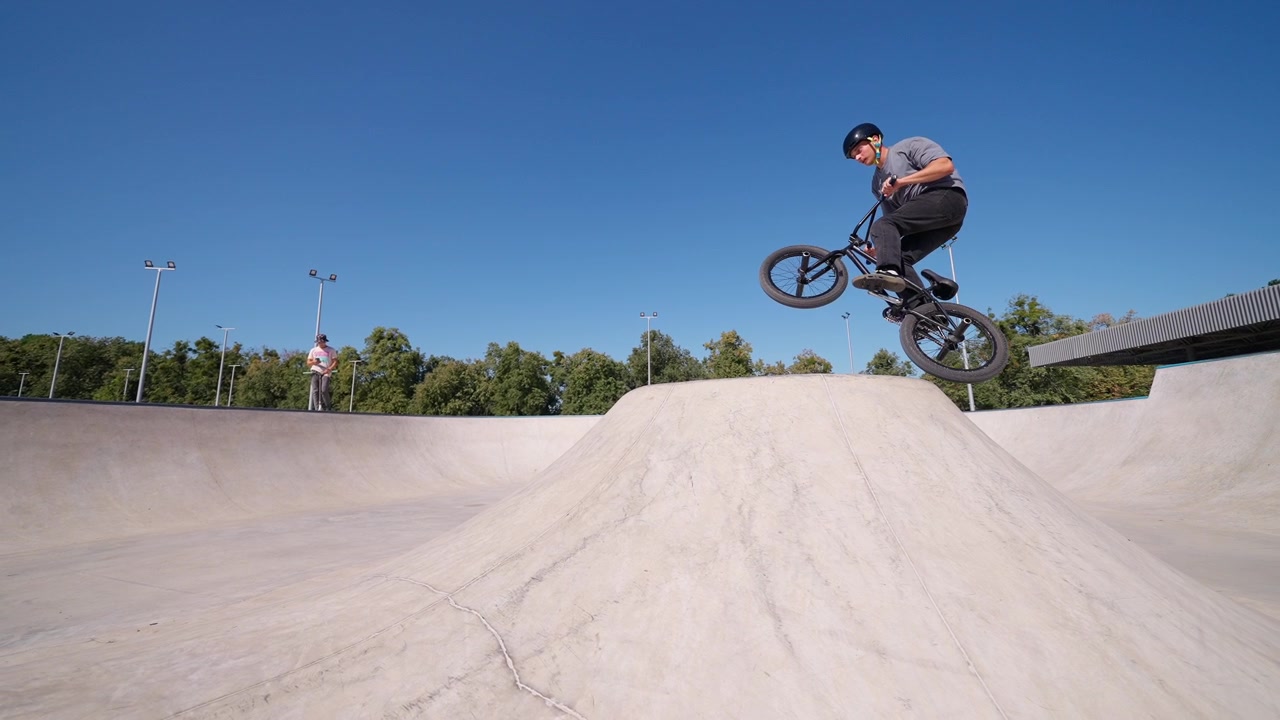 Rider BMX salta una rampa in uno skatepark di cemento