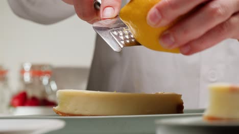 chef zesting lemon over cheesecake