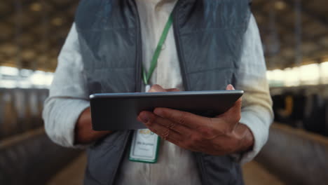 Hände-Tippen-In-Nahaufnahme-Auf-Den-Tablet-Bildschirm.-Konzentrierte-Arbeit-Als-Viehhalter-Im-Kuhstall.