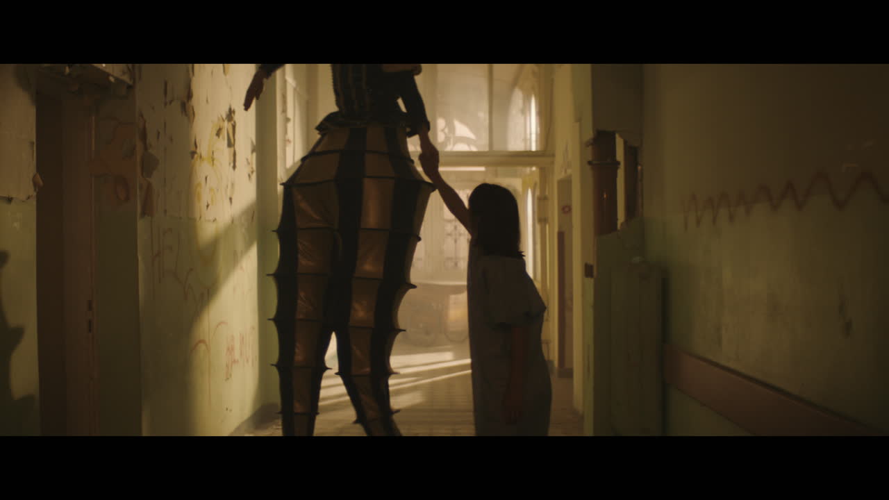A girl and strange clown on stilts in a dark corridor at night