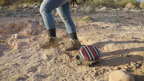 hiker drops camping canteen on desert hike in the dirt and rocks