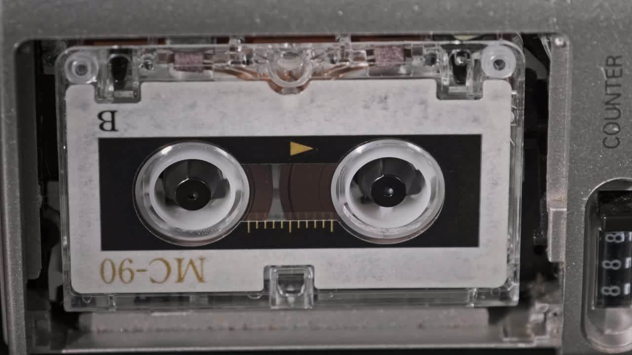 빈 라벨이 있는 빈티지 오디오 테이프가 카세트 레코더에서 회전하고, 클로즈업