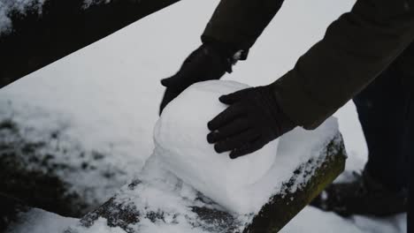 Gloved-hands-pack-down-snow-to-make-snowman,-slow-motion