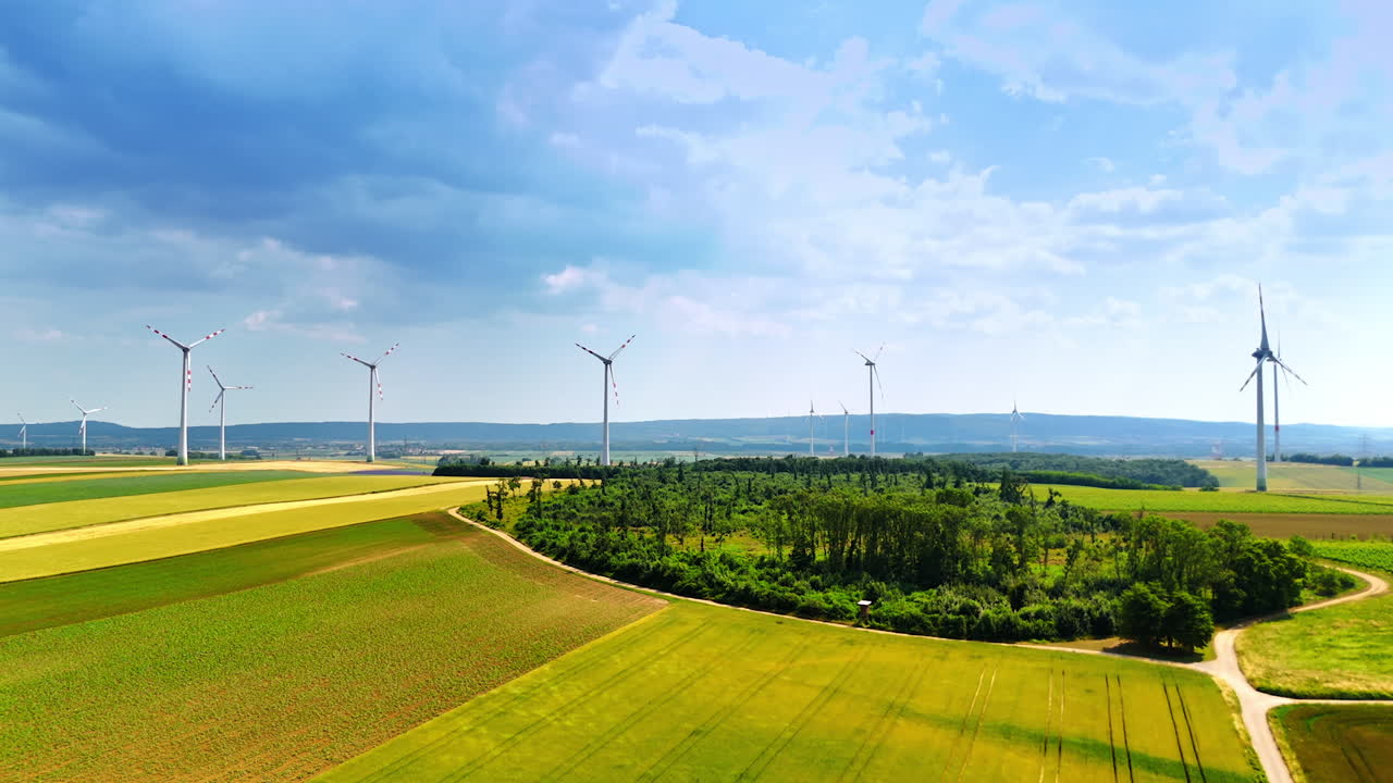Footage above the beautiful agricultural plantations with wind turbines. Green power production