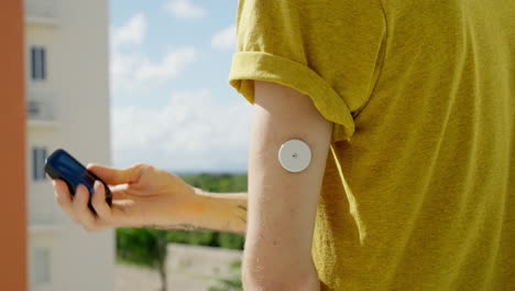 hombre adulto joven comprobando sus niveles de glucosa en sangre en el brazo izquierdo con el sensor freestyle libre 2