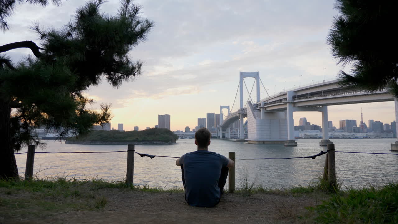 석양에 도쿄 다리로 편안한 남자