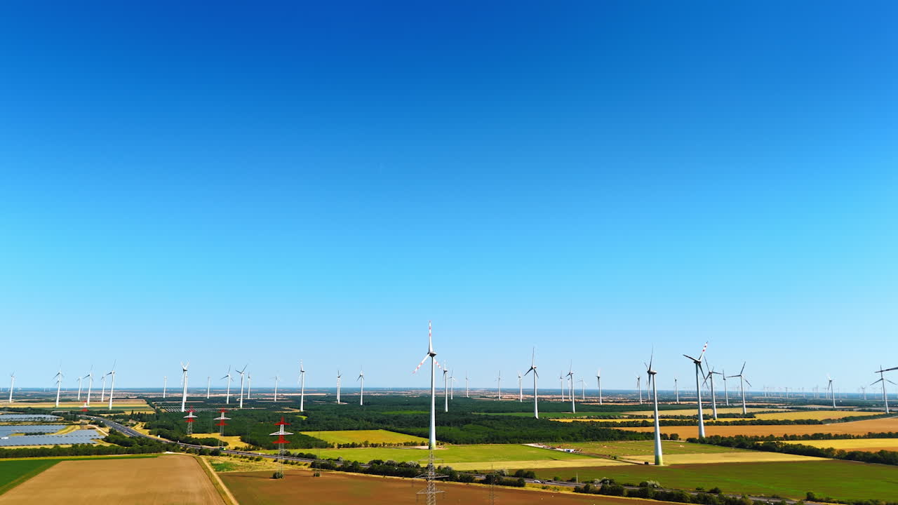 Turbines spin in clear skies. Turbines generate renewable energy in a vast agricultural landscape under a blue sky during daytime