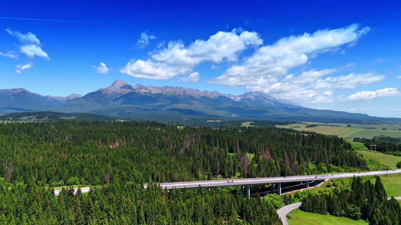 Approaching a freeway crossing the pine tree wood. Spectacular Tatra Mountains at backdrop. Aerial view.