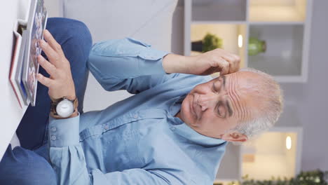 Vertical-video-of-The-old-man-looking-at-the-family-album-is-depressed.