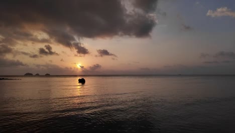 Un-Pequeño-Barco-Navega-Lentamente-Hacia-Una-Romántica-Puesta-De-Sol.