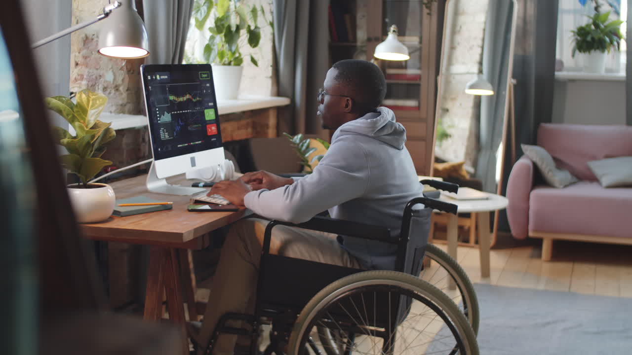 Uomo in sedia a rotelle che lavora al computer