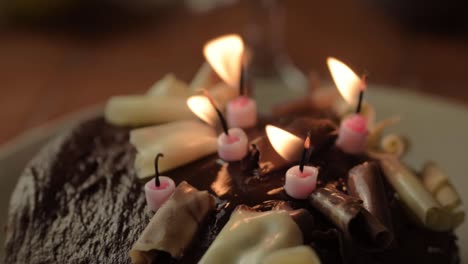 Chocolate-birthday-cake-with-flickering-candles-close-up-shot