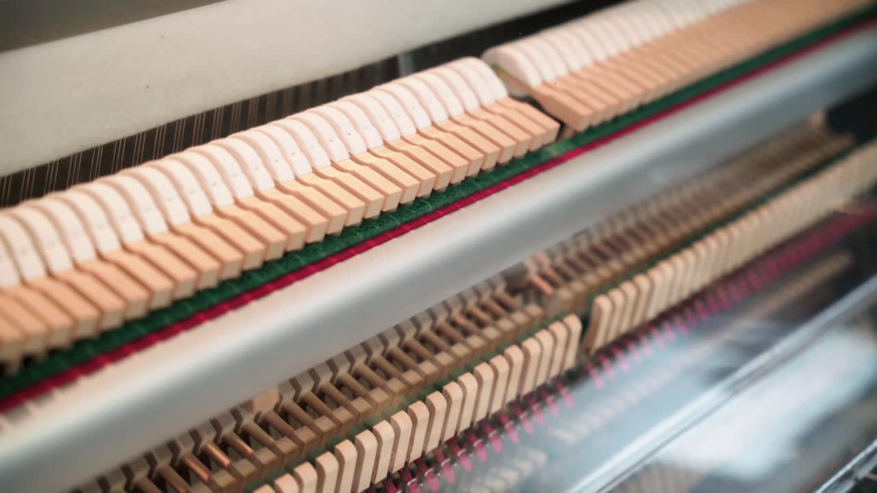 Primo piano del meccanismo meccanico di un pianoforte con martelletti e corde, inquadratura con panoramica a destra.
