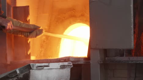 loading molten glass with a shovel into a hot glass furnace