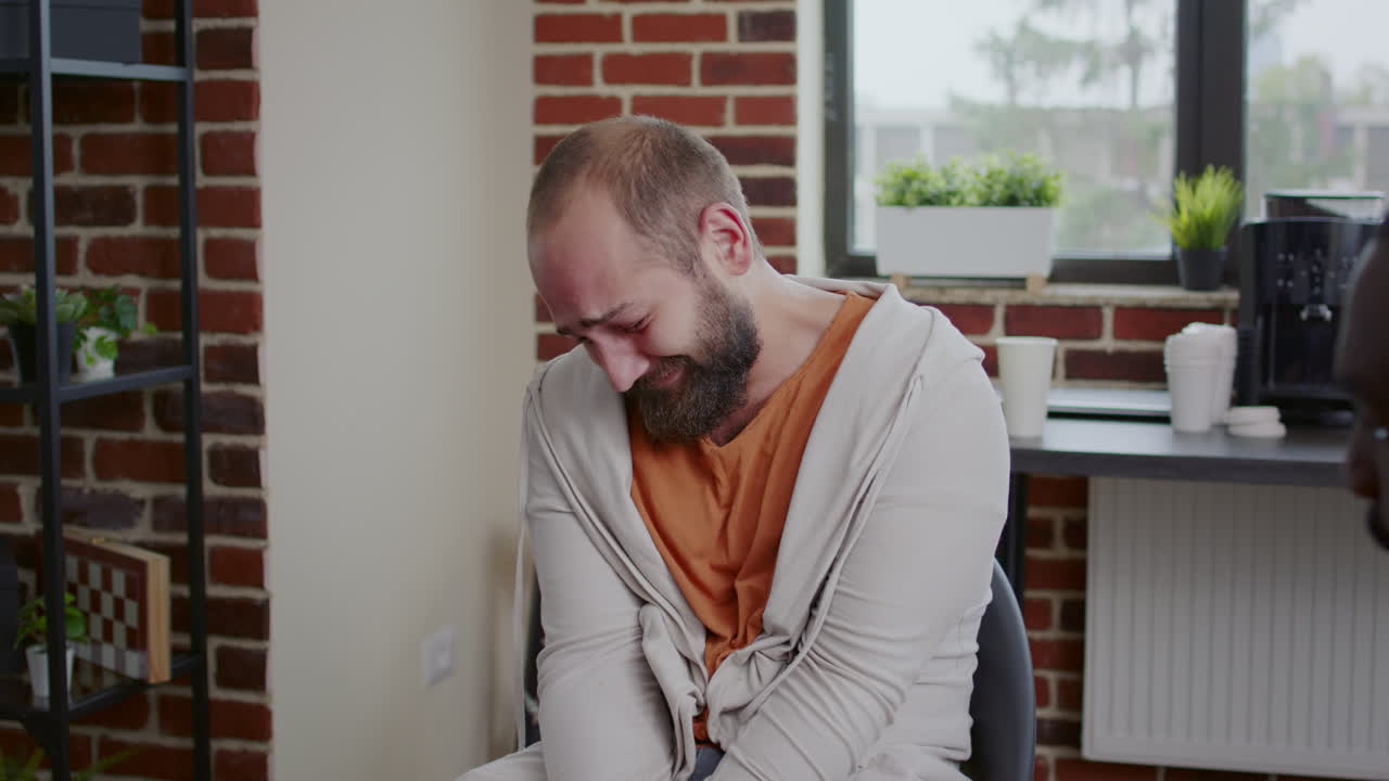 Close up of man having mental breakdown and crying with people at aa therapy session