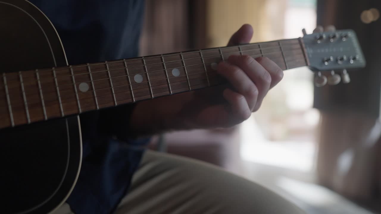 Close up of a Man's hand hand playing an acoustic guitar in a home studio