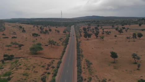 El-Dron-Toma-Una-Toma-Vertical-Hacia-Arriba-De-La-Carretera-De-Tharparkar,-Que-Se-Encuentra-En-Sindh,-Donde-Se-Puede-Ver-El-Vehículo-En-Movimiento