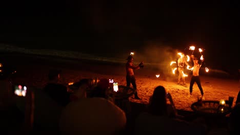 performers juggle fire at night on the beach